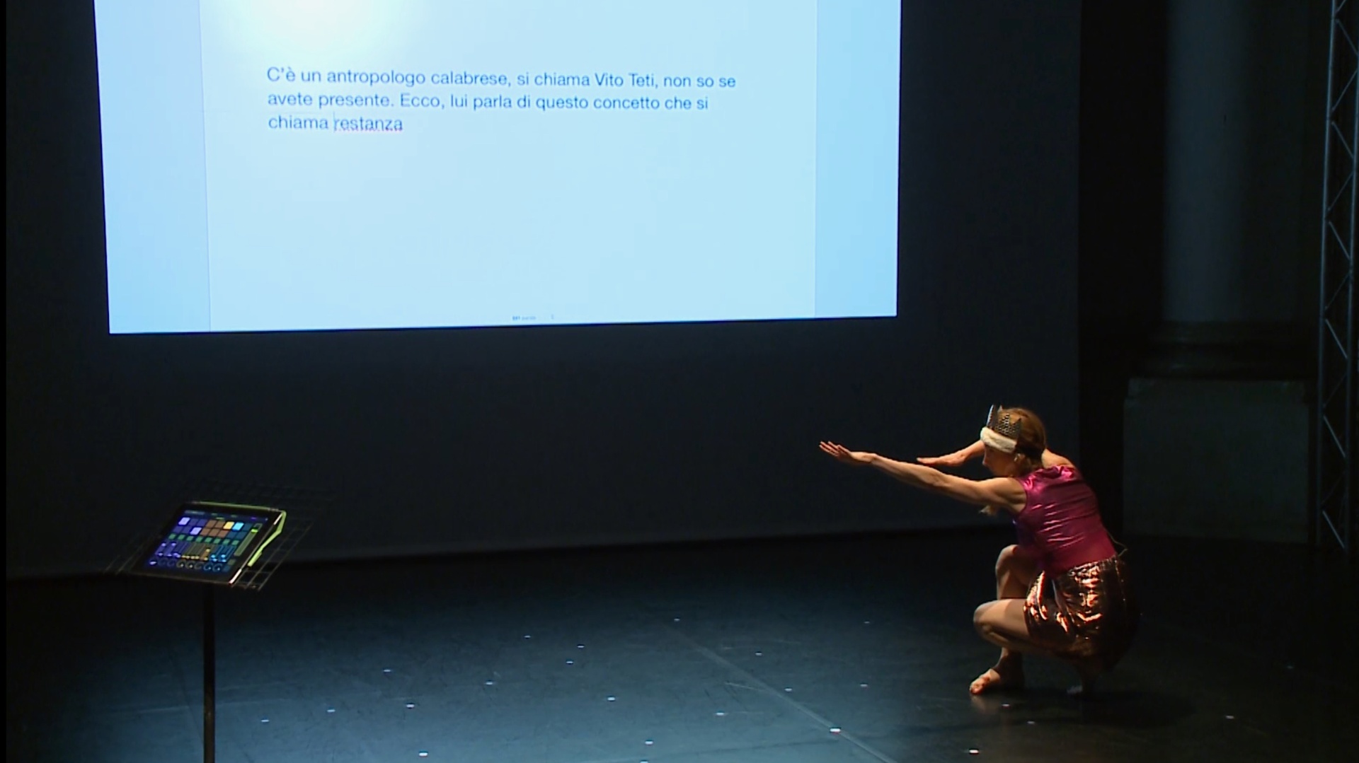 Laura Colomban performing on stage with projected text behind